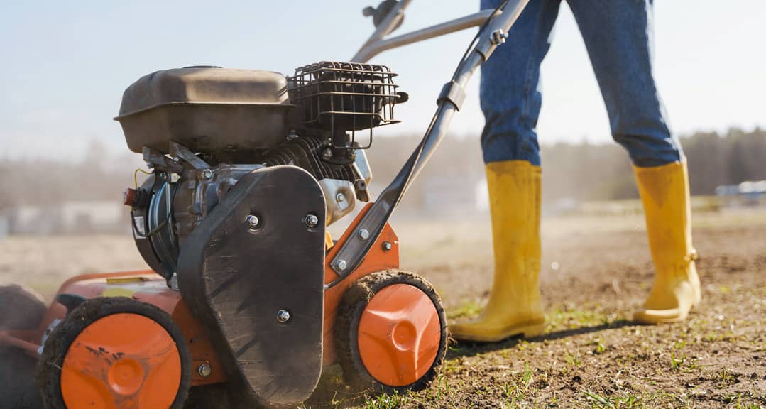 a person pushing a lawn scarification machine